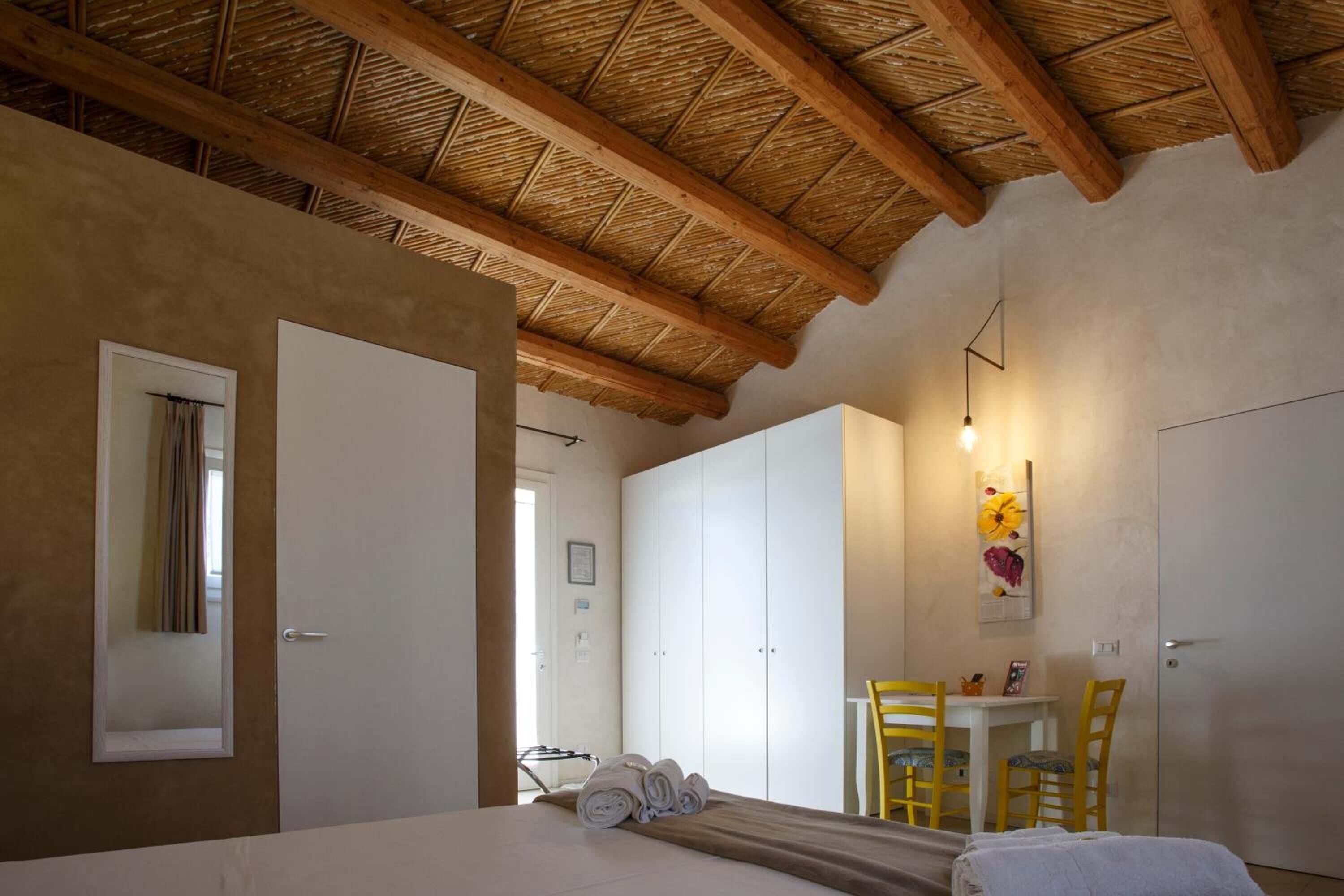 Un dormitorio con cama, armario, escritorio con sillas y una mesa de comedor.