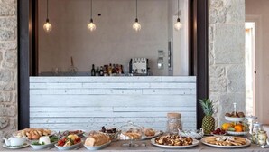 Une table de buffet proposant divers plats et une sélection de vins, le tout dans un cadre rustique avec des murs en pierre et des luminaires suspendus.