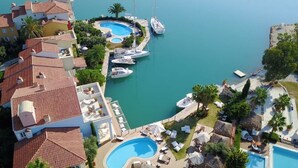 A marina with multiple boats docked, a swimming pool, and a landscaped area with lounge chairs and umbrellas. - Port Alacati Hotel (Cesme)