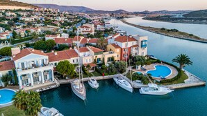 A marina with multiple boats docked, surrounded by residential buildings with red-tiled roofs and balconies. - Port Alacati Hotel (Cesme)