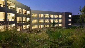 A modern building with multiple balconies and windows, surrounded by lush greenery. - Cresta Maun (Maun)