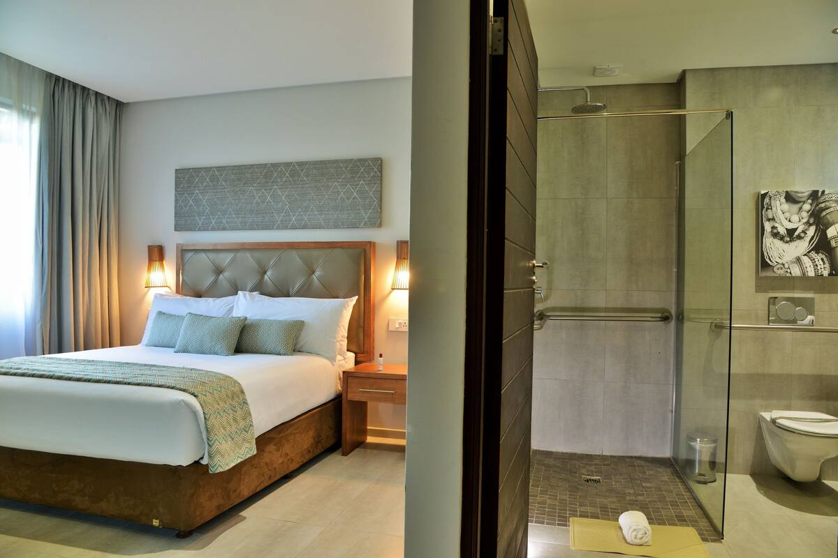 Una habitación de hotel con una cama grande, lámparas de noche y un adorno de pared decorativo.