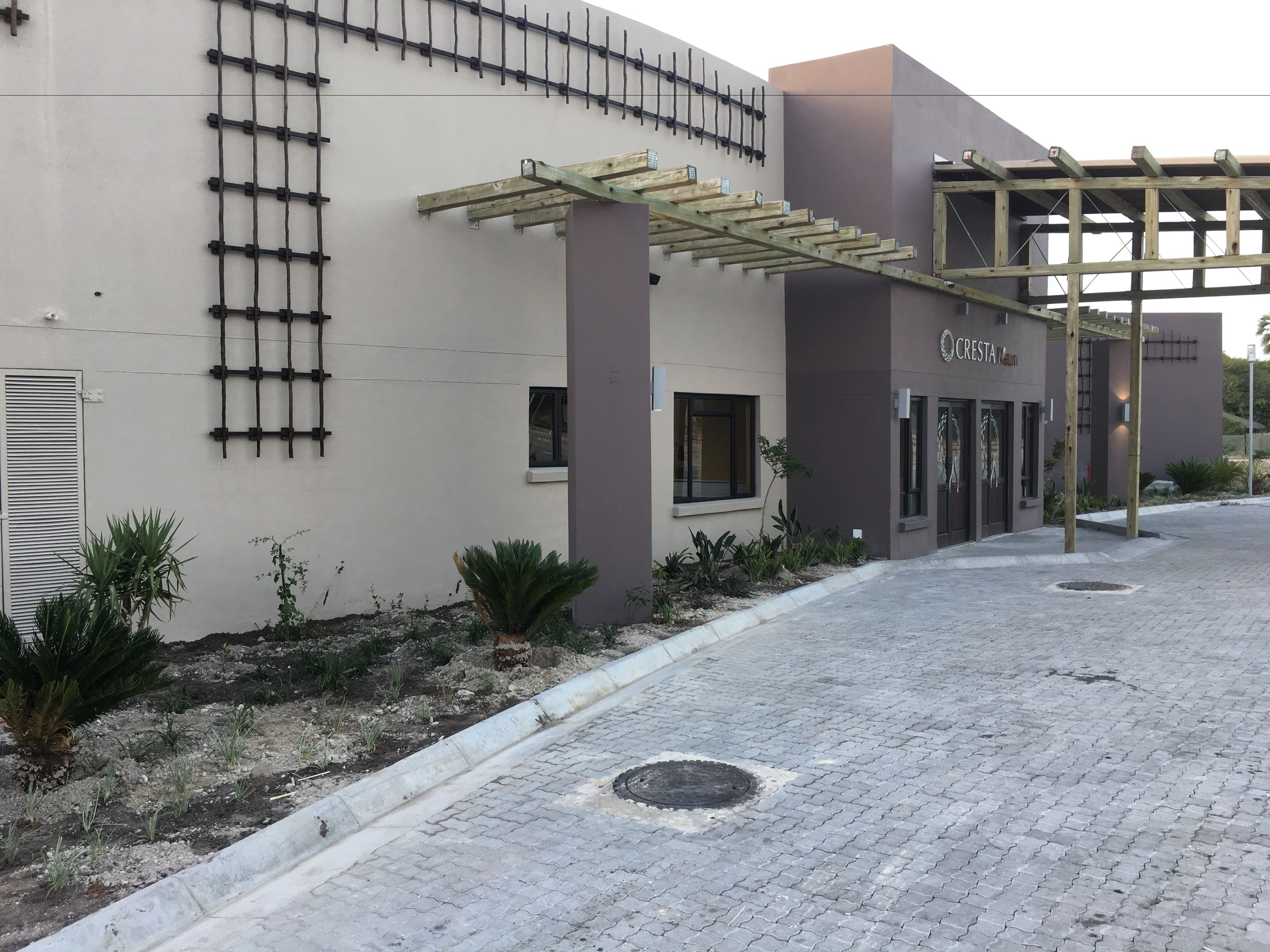 Un bâtiment à l’architecture moderne, doté d’une entrée en forme de pergola, d’une entrée sécurisée par un portail et d’une enseigne indiquant « Hôtel CRESTA ».