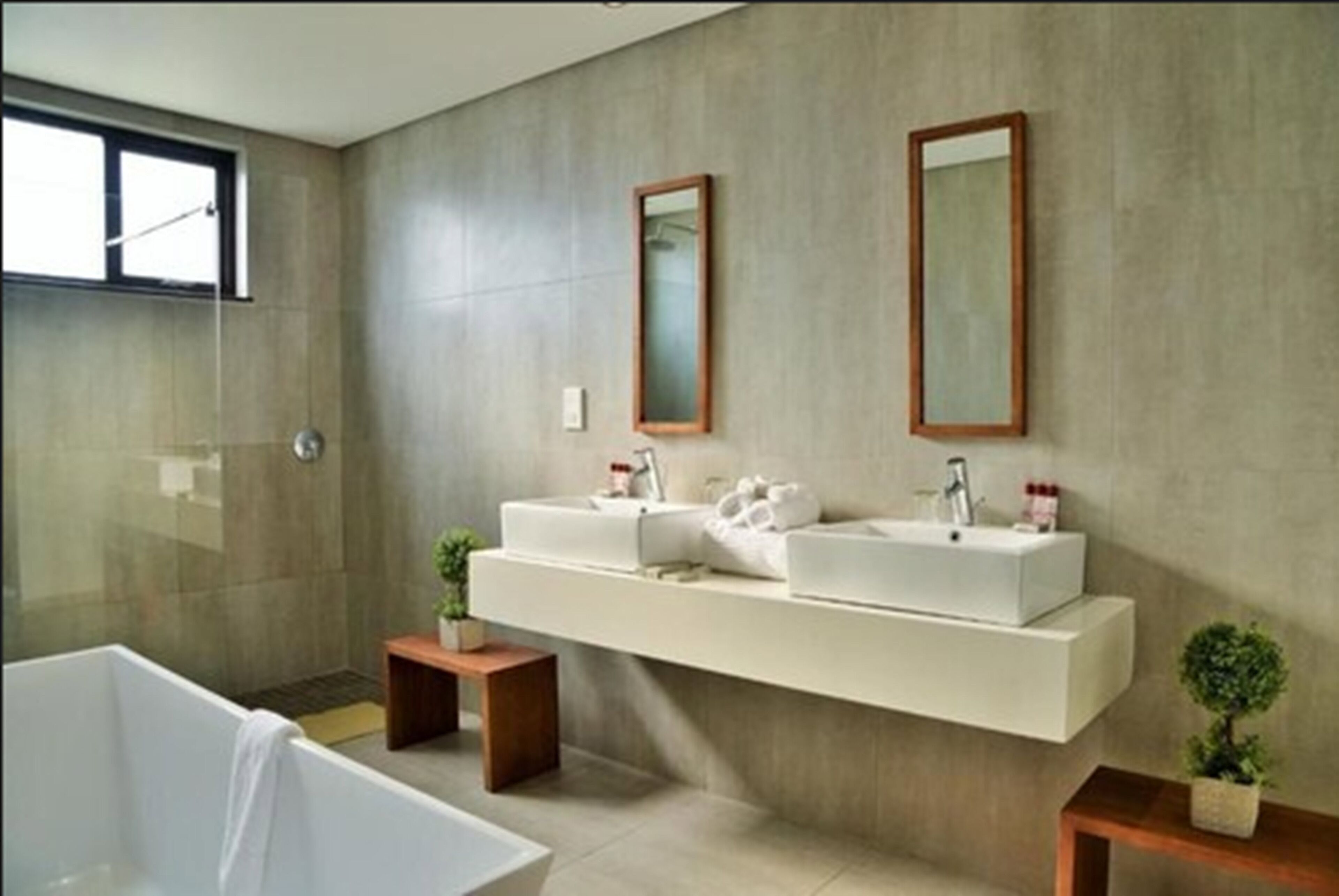 A modern bathroom with a large bathtub, two sinks, and a floating vanity.