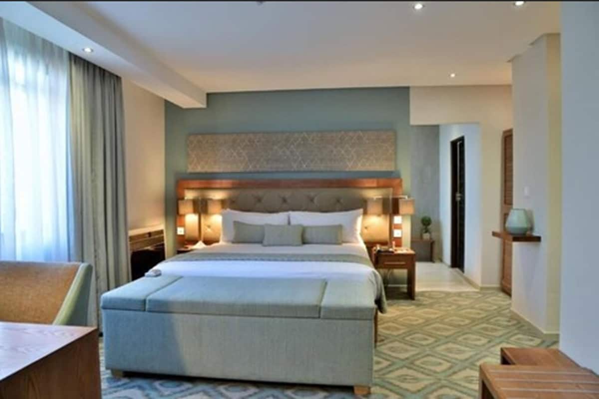 Una habitación de hotel con una cama grande, mesitas de noche, un escritorio y una silla.