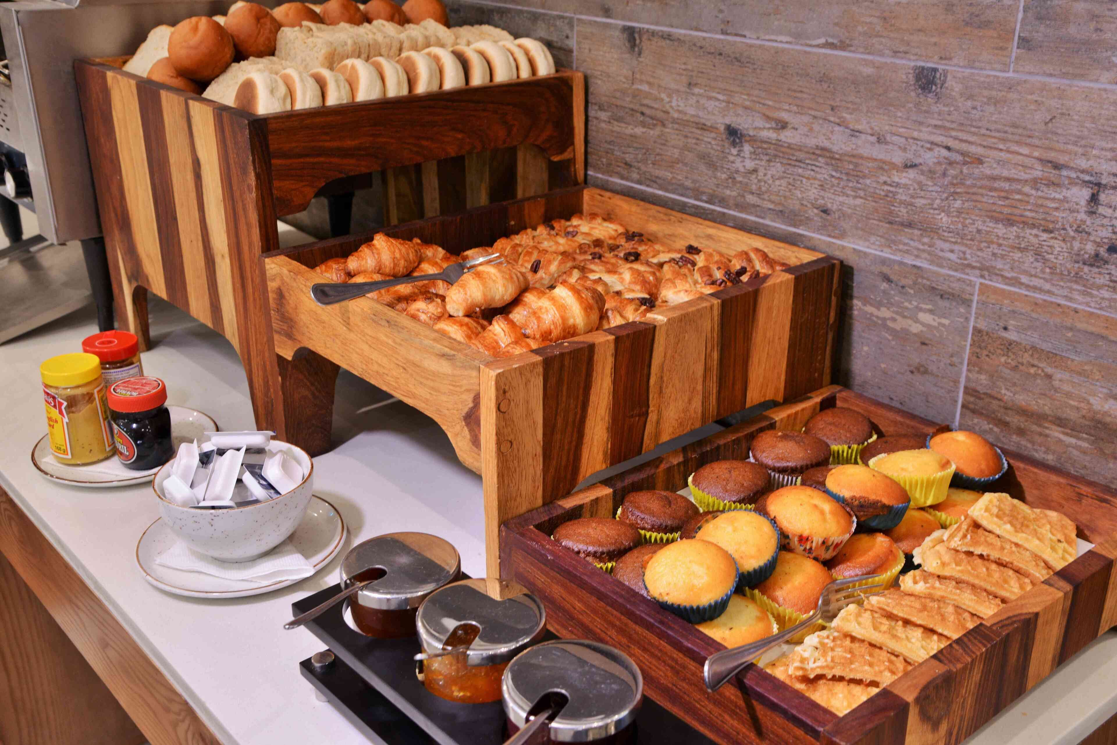 A buffet with various baked goods including muffins, croissants, and pastries.