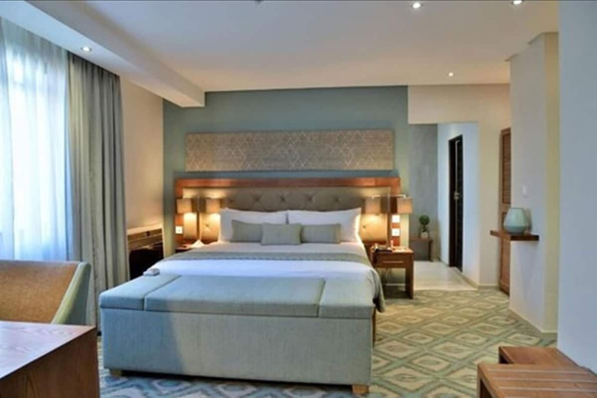Una habitación de hotel con una cama grande, mesitas de noche, un escritorio y un suelo estampado.