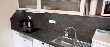 A compact kitchen with a dishwasher, a sink, and a microwave.