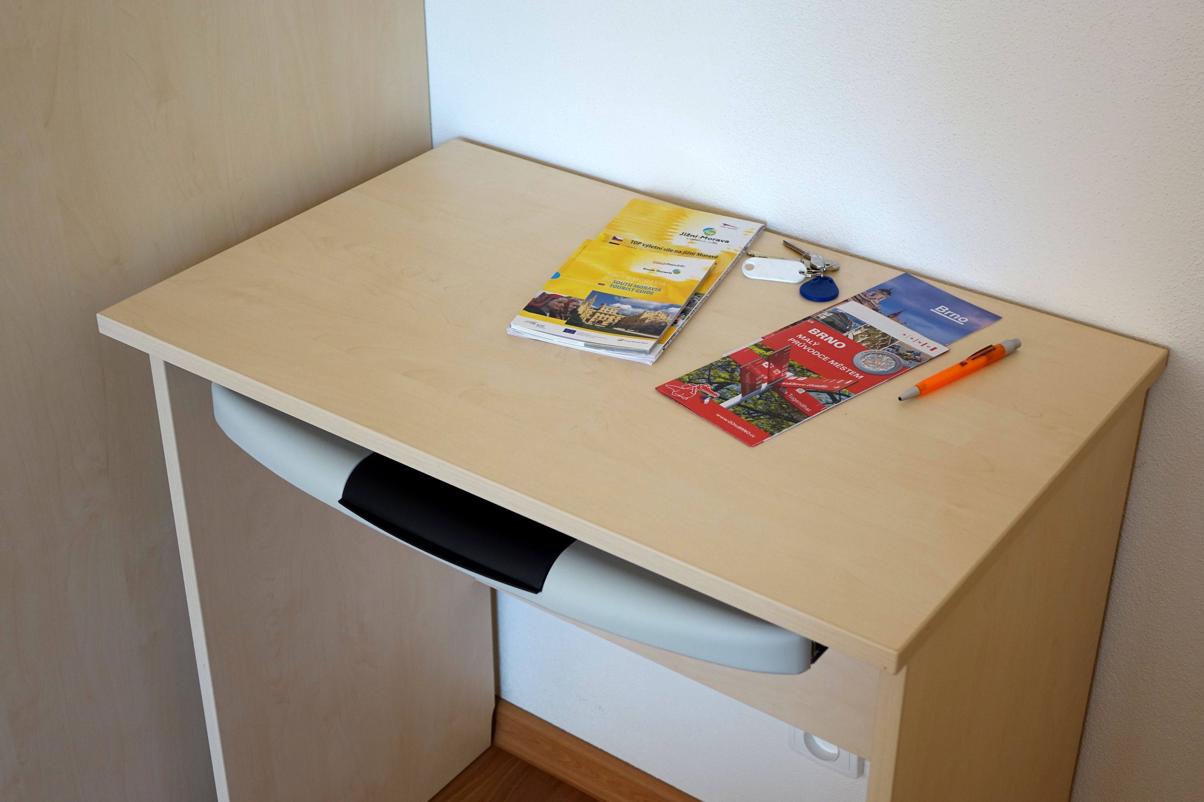 Ein Schreibtisch in der Ecke mit einer Zeitschrift, einem Stift und einem Schlüsselbund.