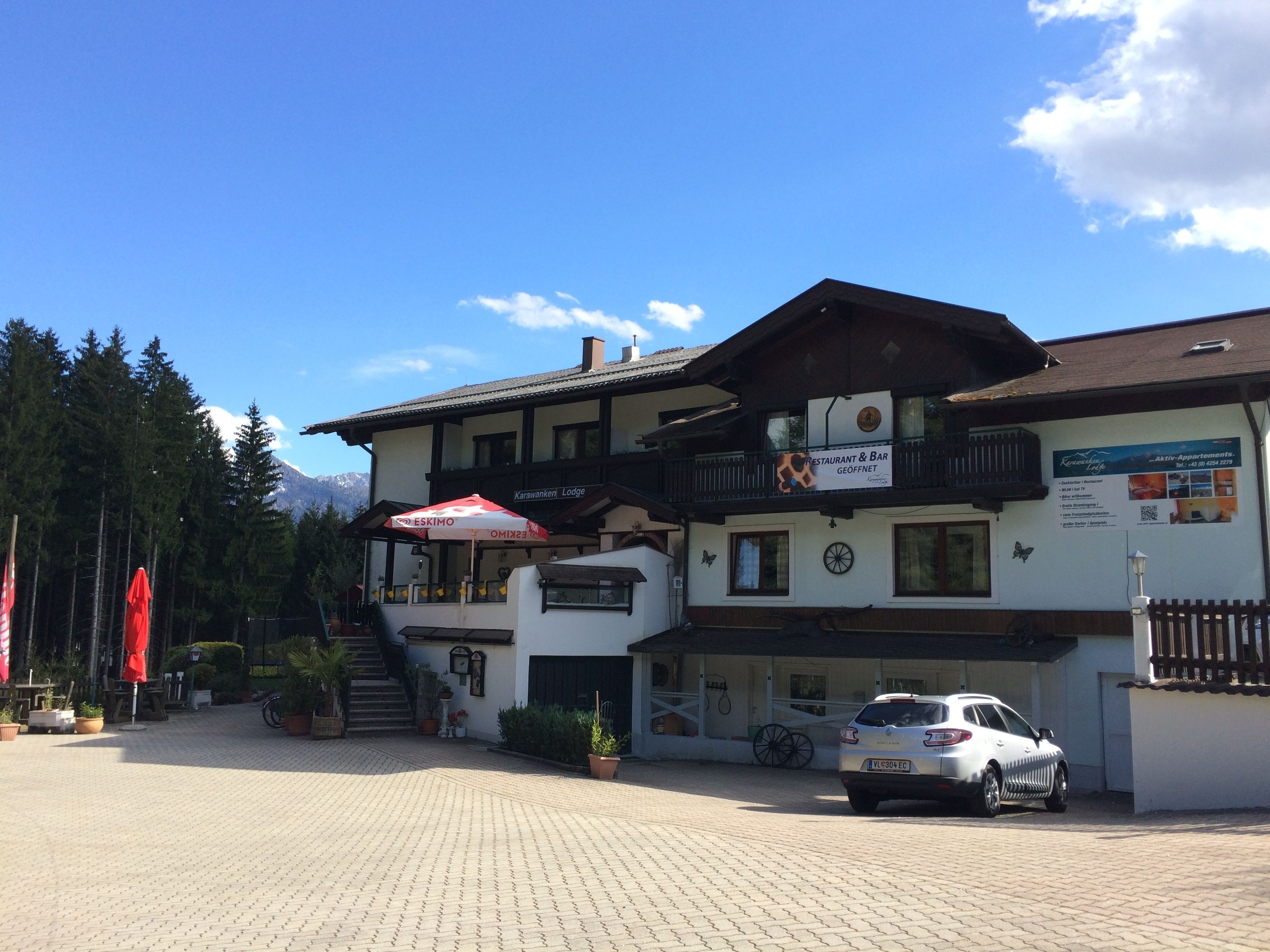 A two-story building with a restaurant and bar, a car parked in front, and a mountainous backdrop.