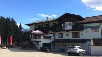 A two-story building with a restaurant and bar, a car parked in front, and a mountainous backdrop.