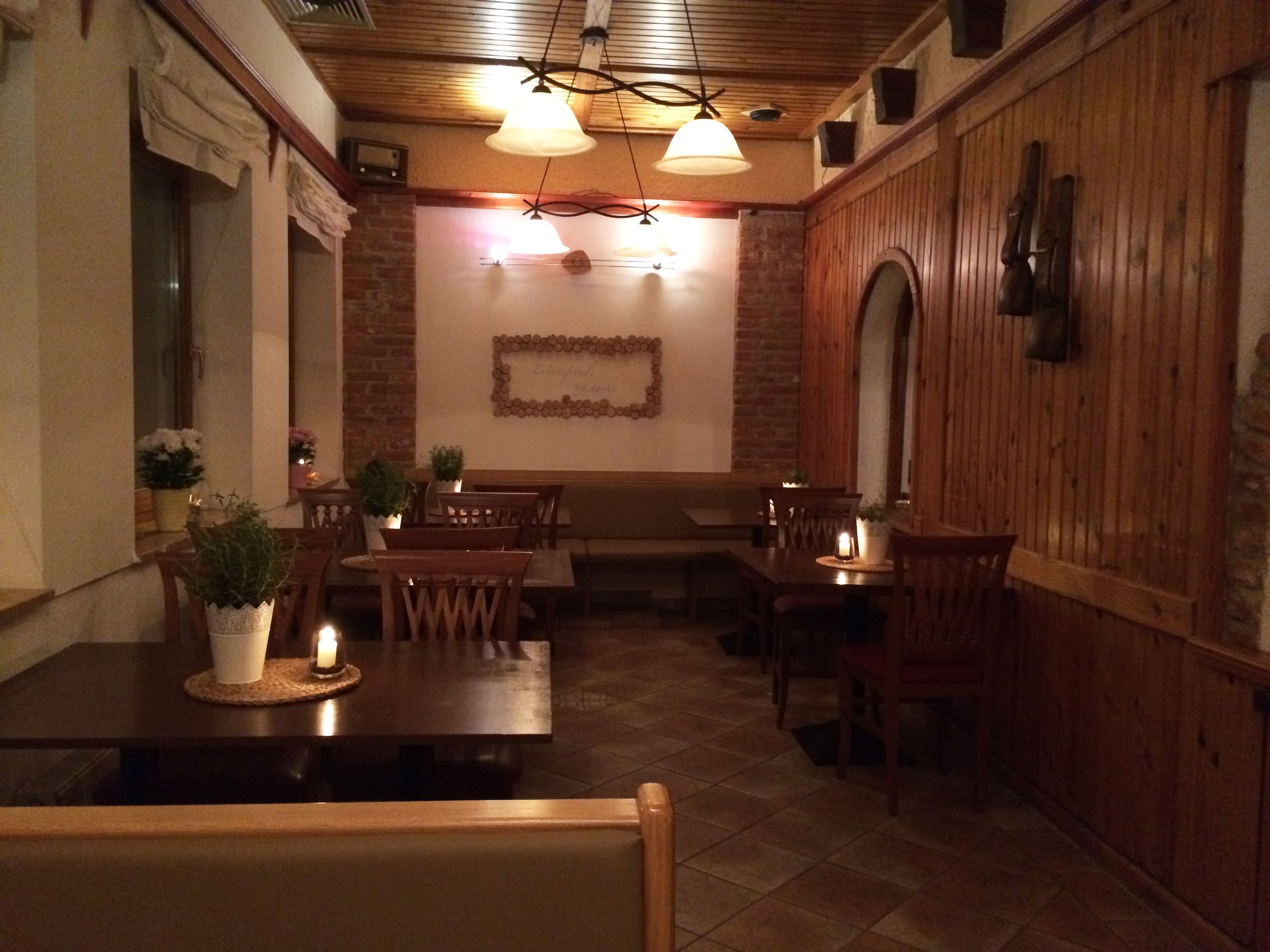 L’intérieur d’un restaurant avec des tables et des chaises en bois, des murs en briques et des lampes suspendues.