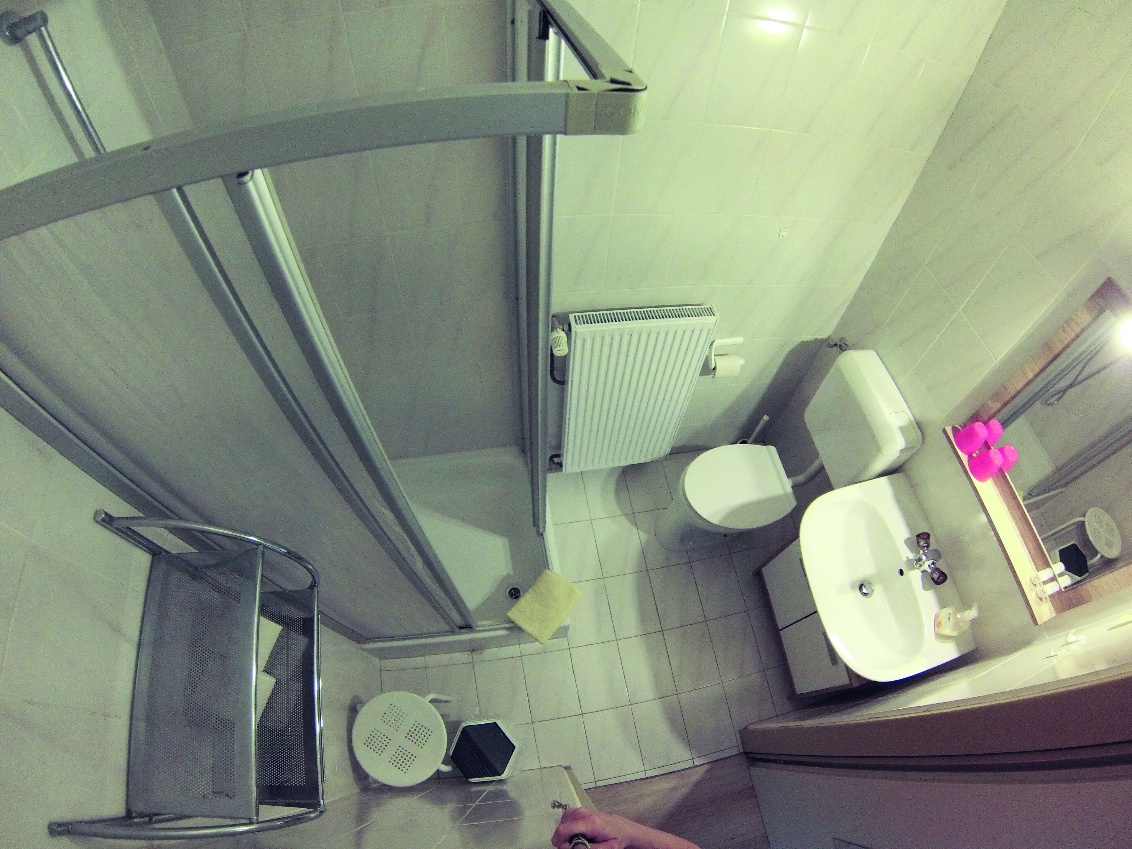 Un bagno con doccia, toilette, lavandino e specchio.