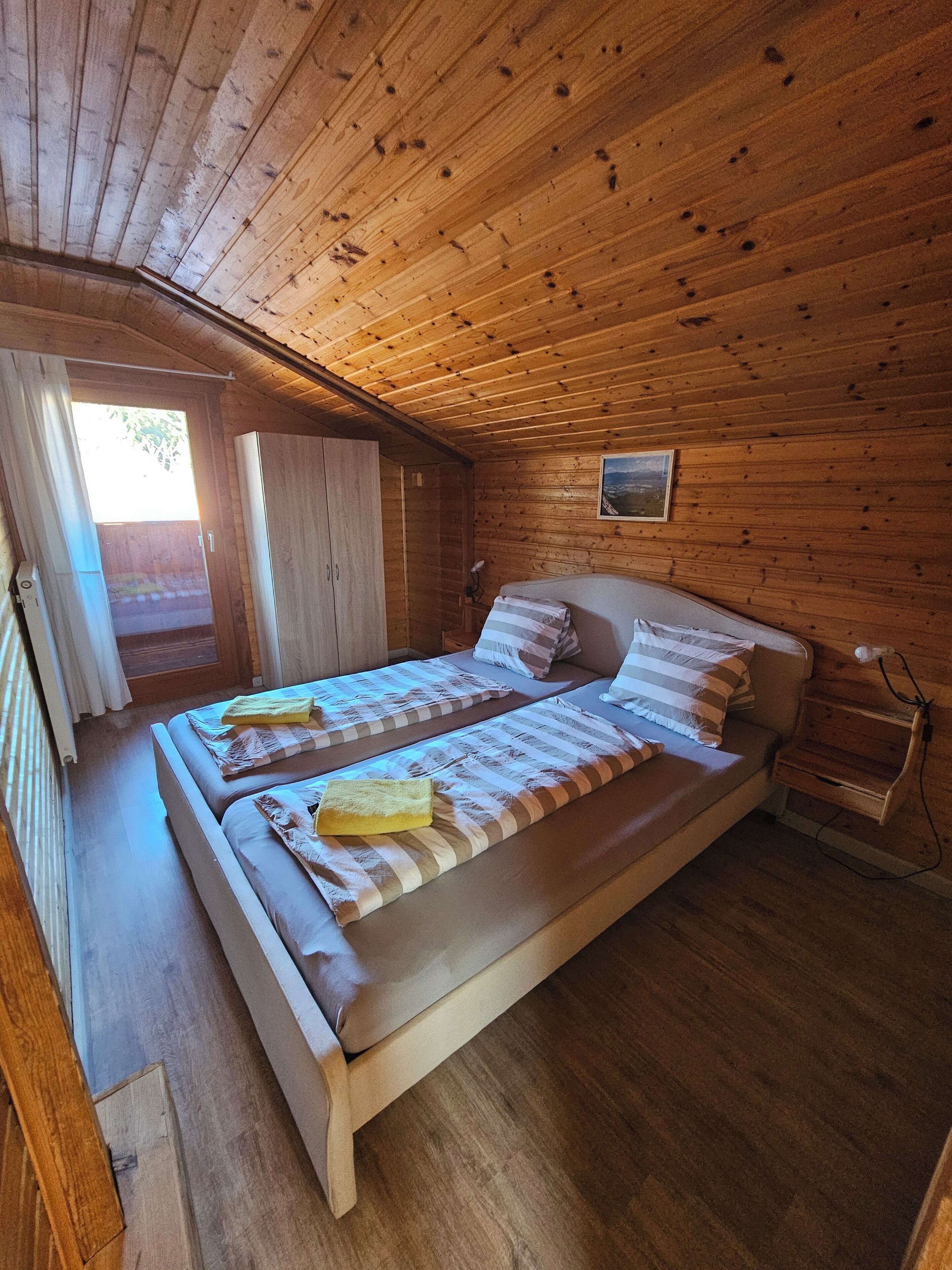 Une chambre dans une cabane en bois, avec deux lits, une petite fenêtre et un plafond en bois.