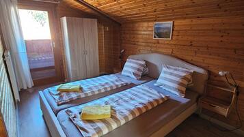 Une chambre dans une cabane en bois, avec deux lits, une petite fenêtre et un plafond en bois.
