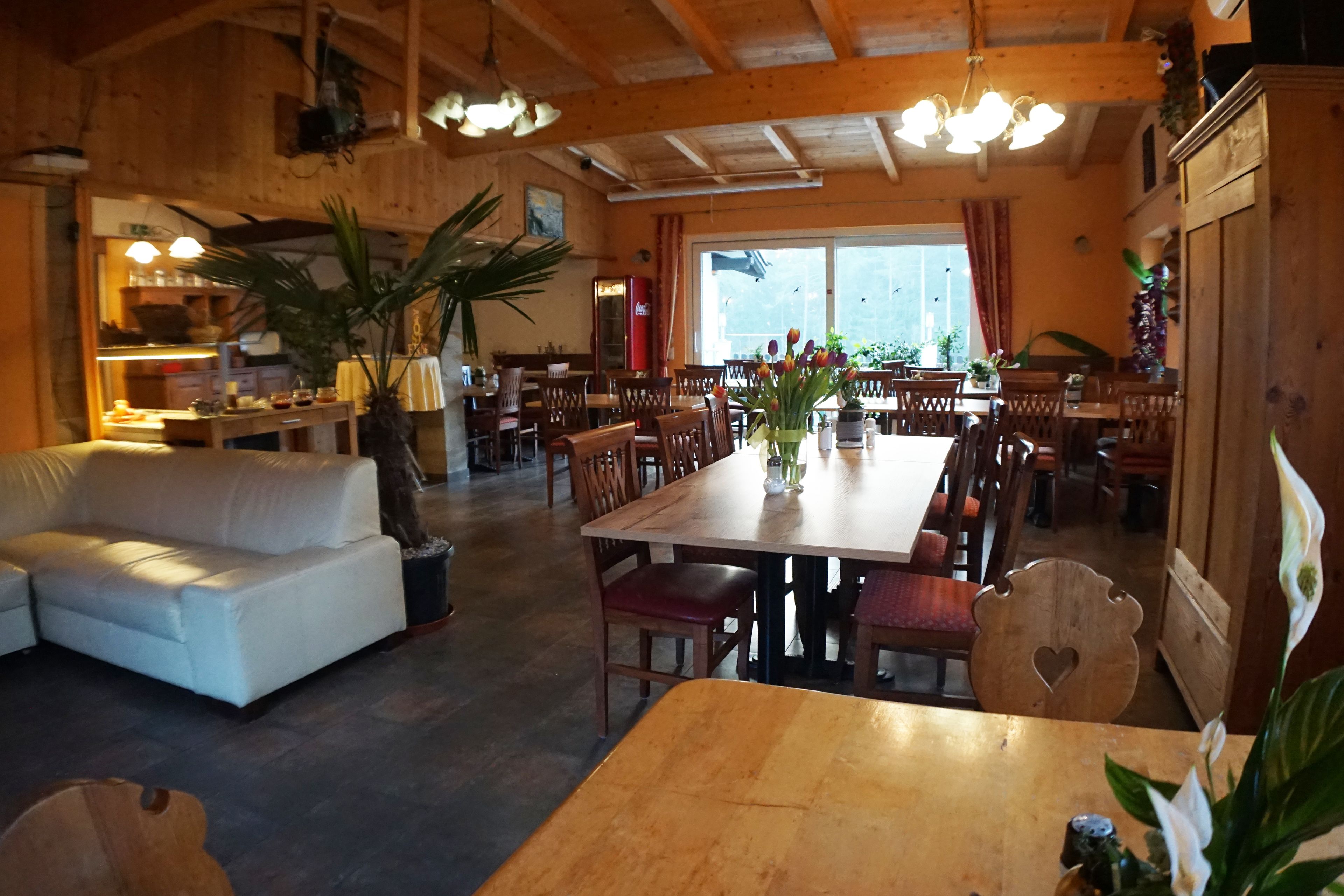 Un comedor acogedor y rústico con muebles de madera, un sofá blanco y un amplio ventanal que proporciona luz natural.