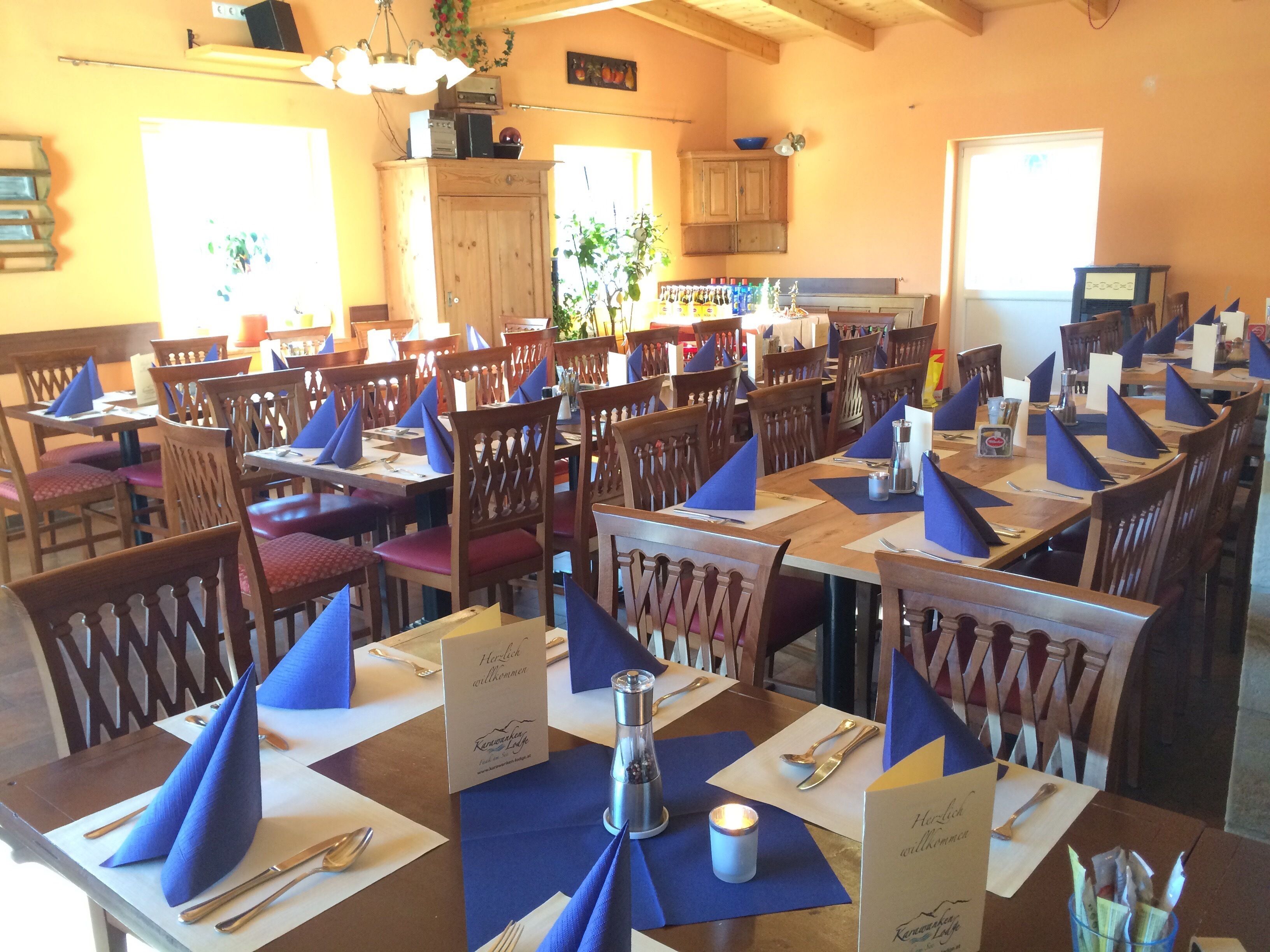 Un restaurante con varias mesas dispuestas para comer, cada una con servilletas, cubiertos y menús azules.