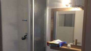 A bathroom with a glass shower enclosure, a white sink, and a mirror above the sink.