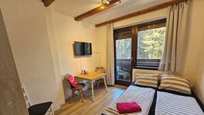 Une chambre avec deux lits, un bureau, une chaise et une télévision.