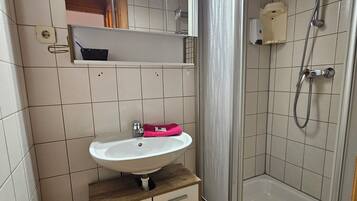 A bathroom with a sink, mirror, shower, and tiled walls.