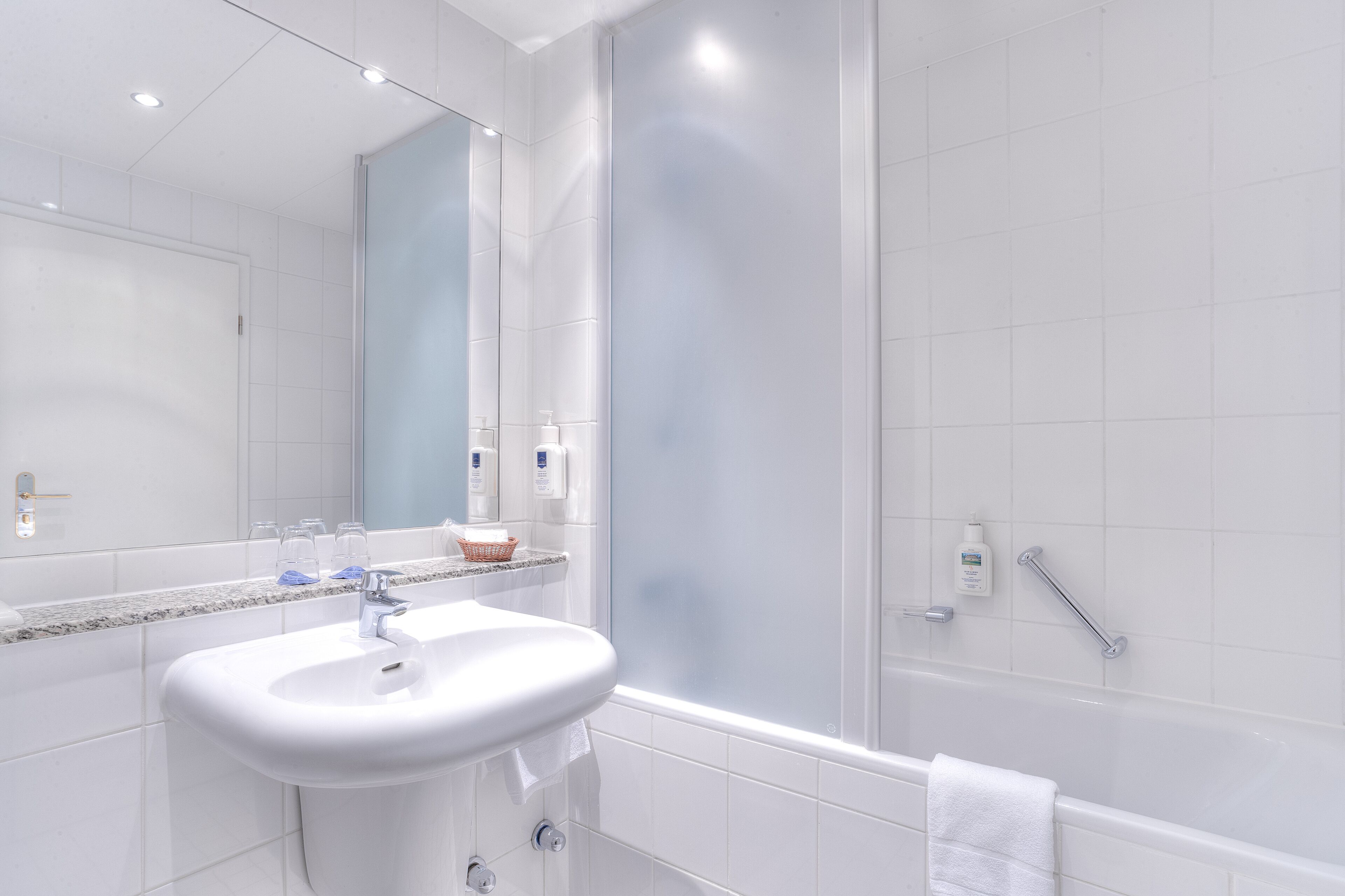 Ein modernes Badezimmer mit Waschbecken, Spiegel und Badewanne in Weiß.