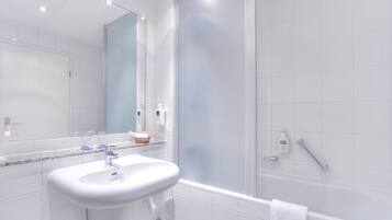 Ein modernes Badezimmer mit Waschbecken, Spiegel und Badewanne in Weiß.