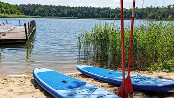 A lakeside setting with paddleboards and a dock.