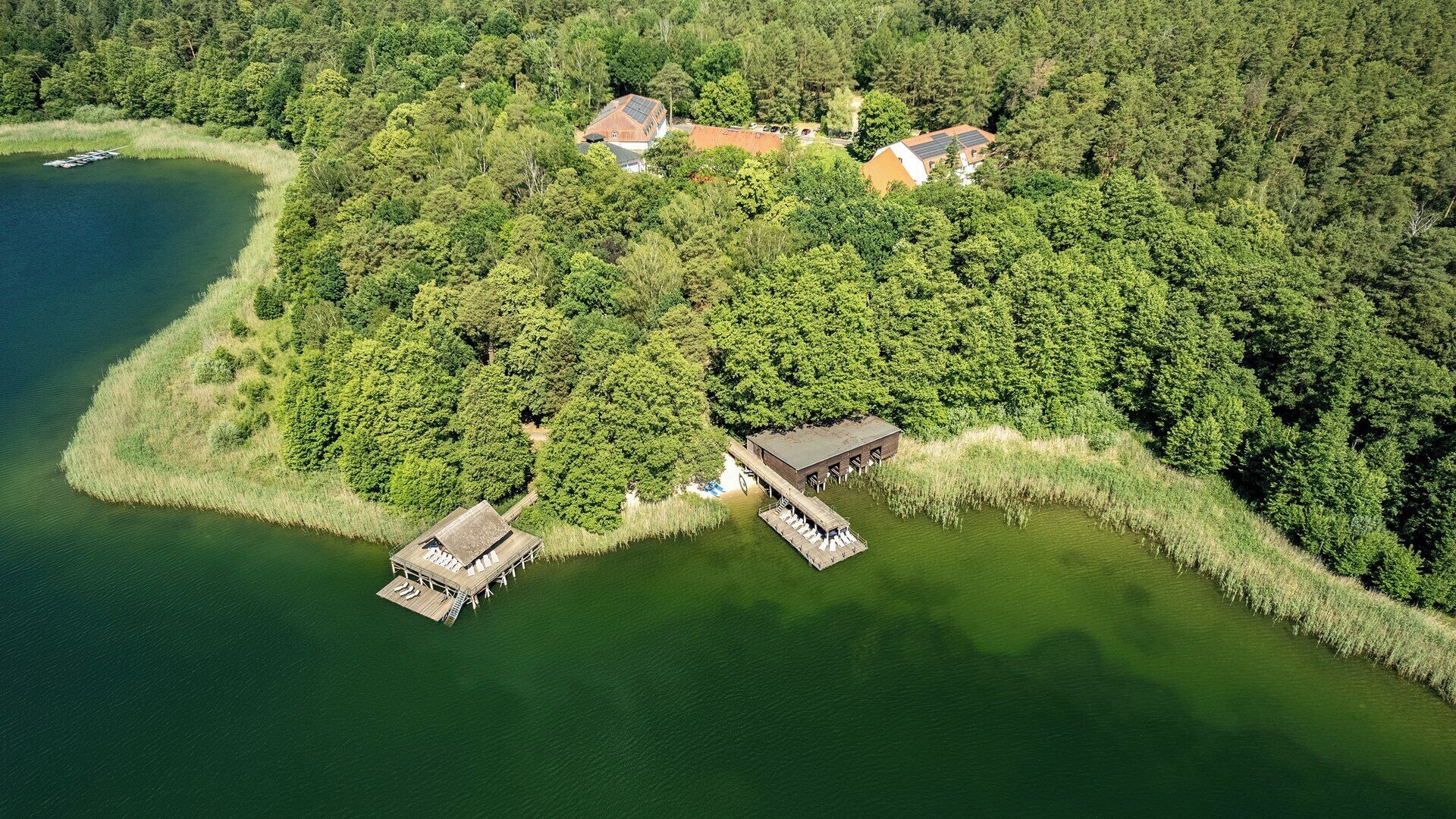 An aerial view of a lakeside property with multiple buildings, docks, and a boat.