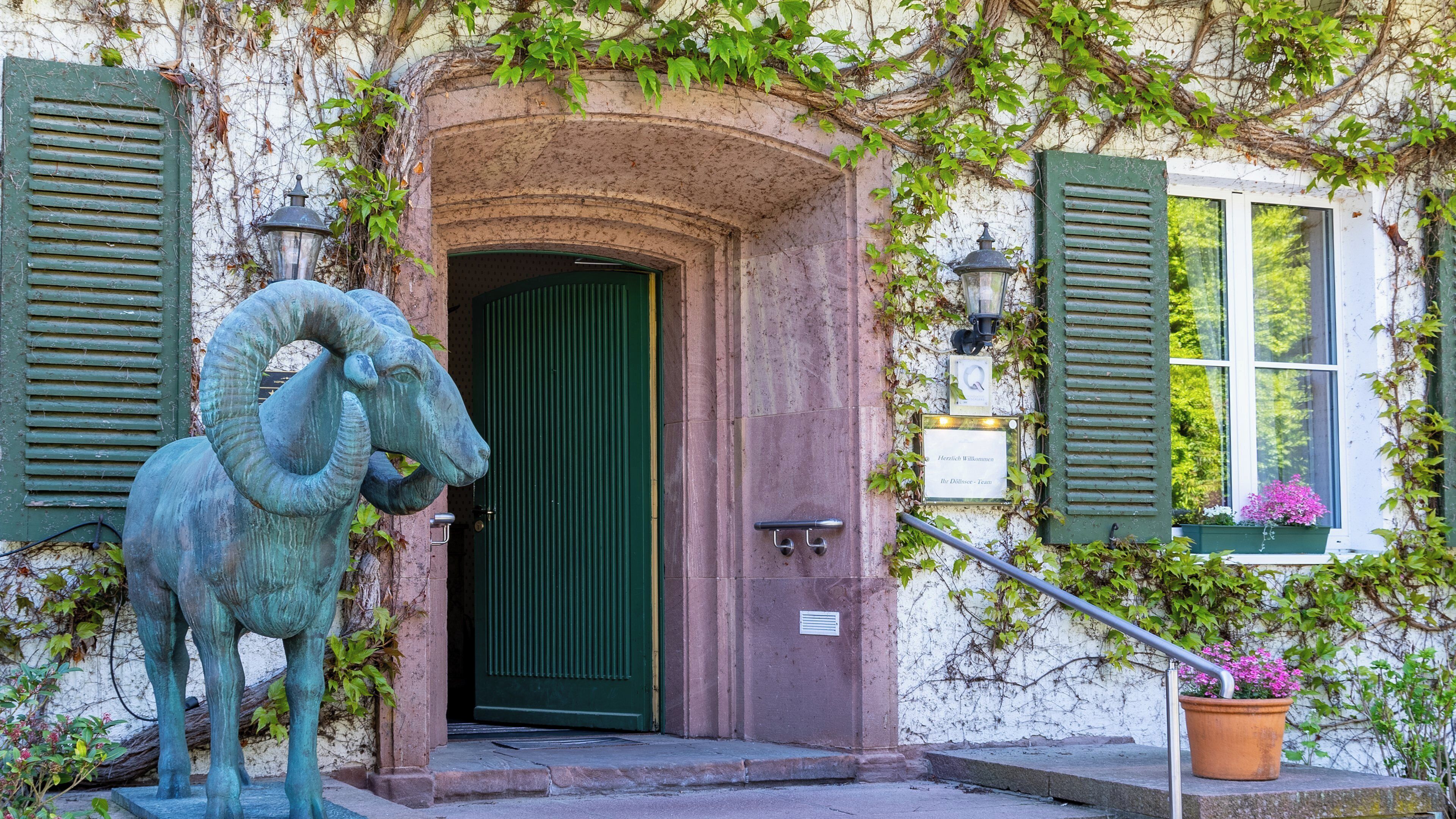 Un bâtiment avec une porte verte, une statue de bélier et une plaque commémorative.