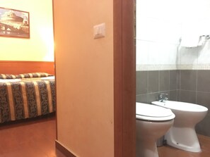 Un baño con dos inodoros, una zona de ducha y un banco estampado.