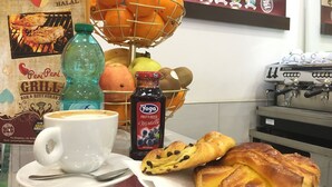 A breakfast setting with a coffee cup, a basket of oranges, a bottle of juice, and pastries. - Best Location in Rome (Rome)