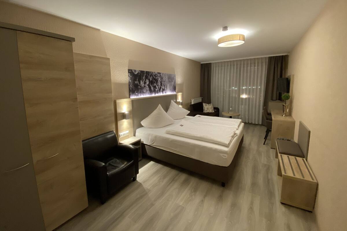 Una habitación de hotel moderna con una cama grande, un escritorio, una silla y una pequeña mesa.