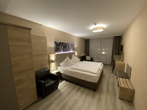 A modern hotel room with a large bed, a desk, a chair, and a small table. - Hotel Traumblick (Cochem)