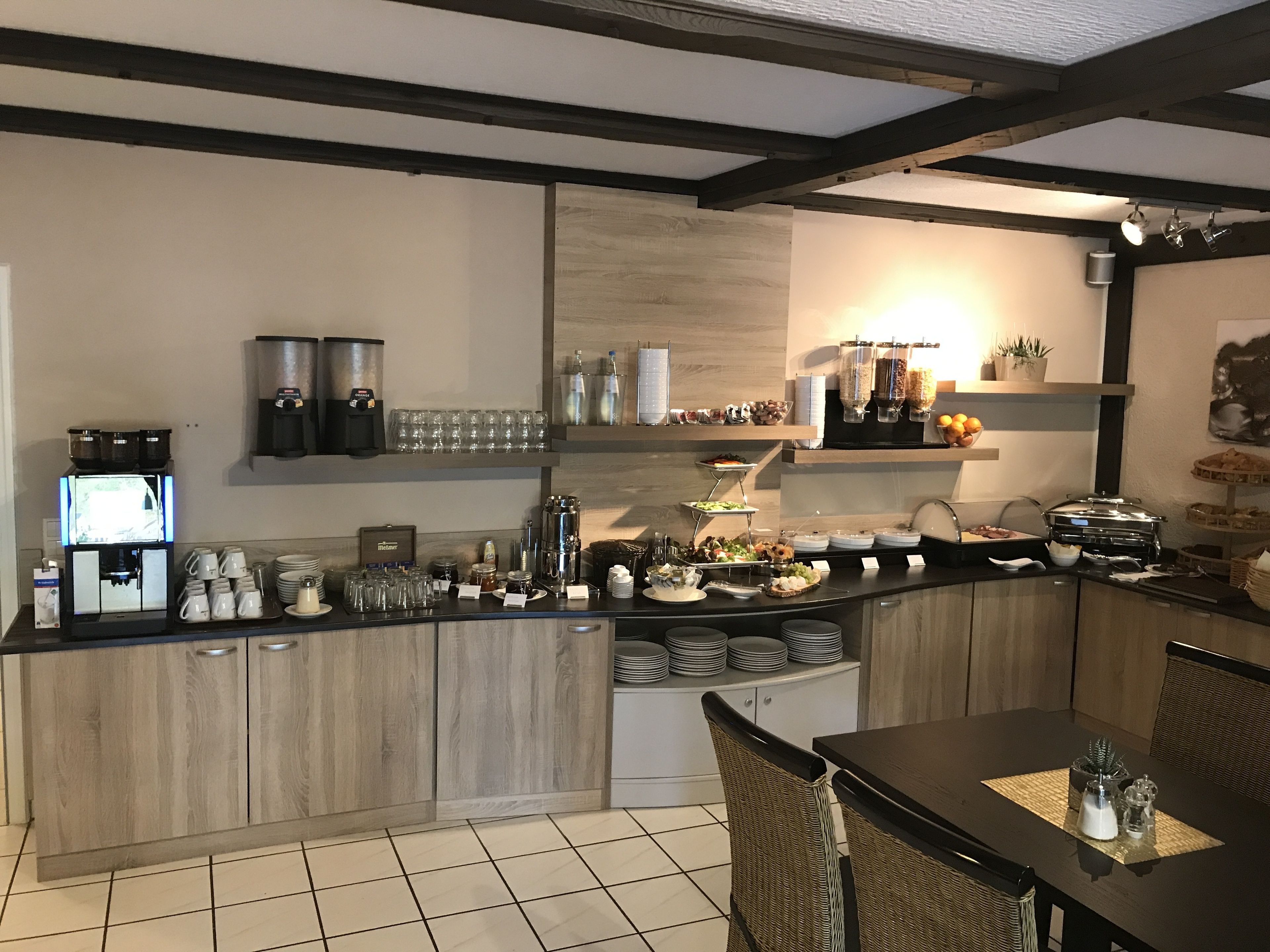 A modern kitchen with a central island, built-in appliances, and a dining area with wicker chairs.