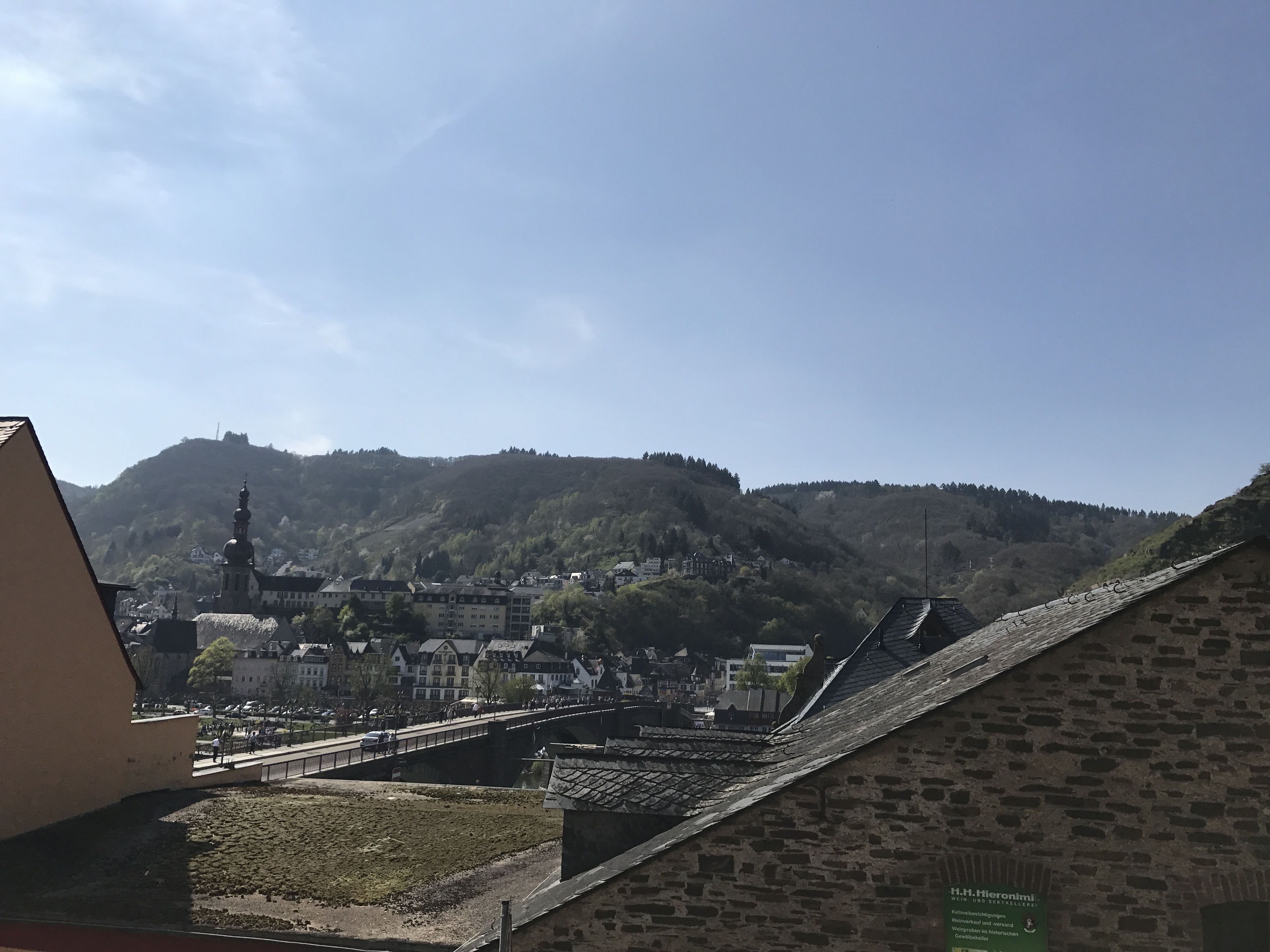 A town with a prominent hill, a bridge, and a building with a sign.