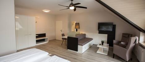 Un dormitorio moderno con cama, escritorio, silla, sofá y televisor.