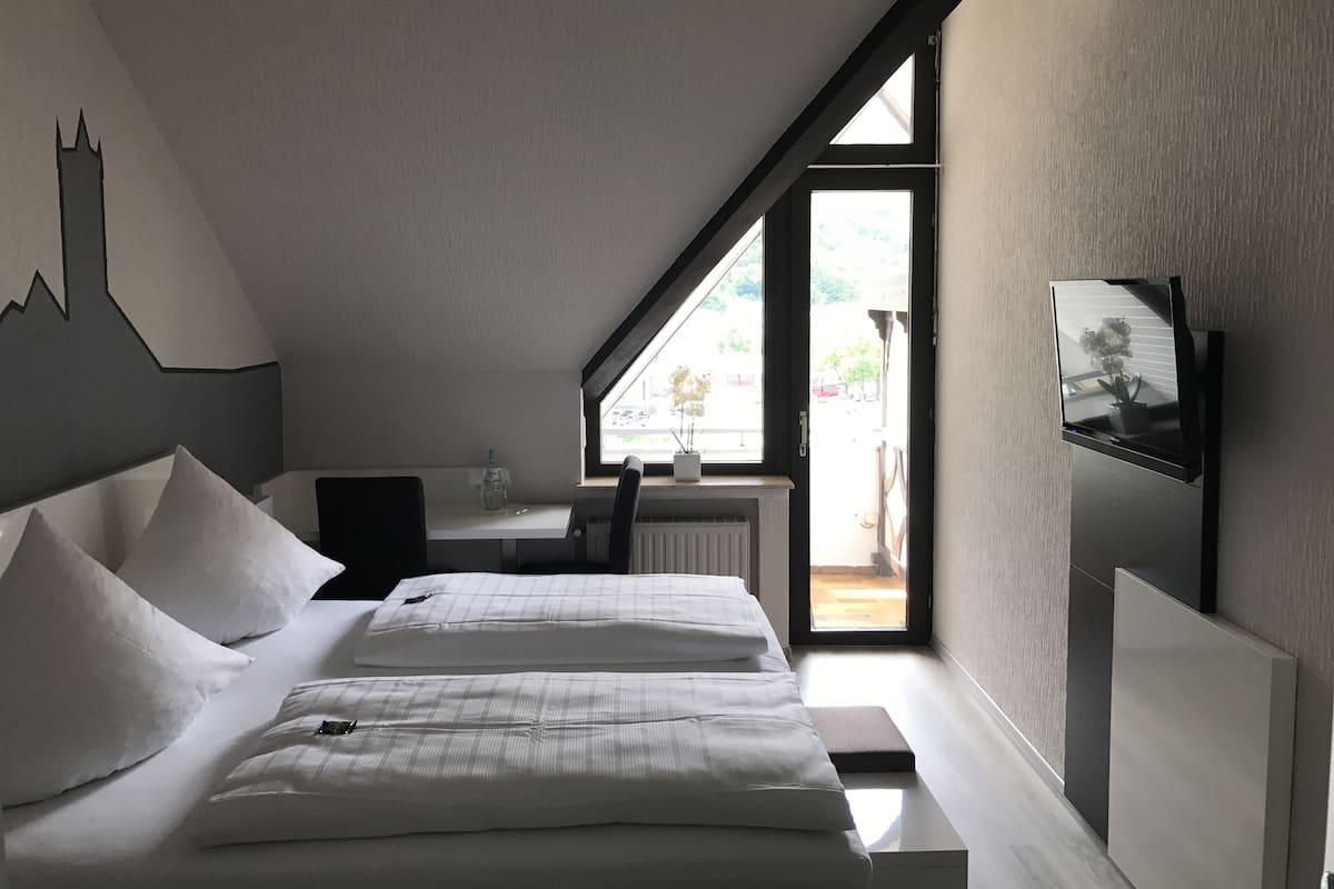 Un dormitorio con cama, escritorio y ventana.