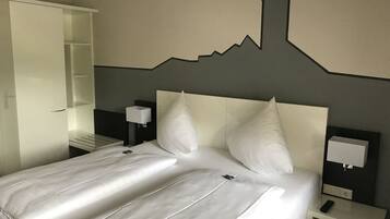 Une chambre d’hôtel comprenant un lit, une table de chevet, un téléviseur fixé au mur et une armoire.