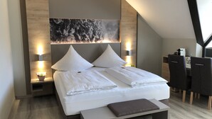 A modern bedroom with a bed, bedside tables, a desk, and chairs. - Hotel Traumblick (Cochem)