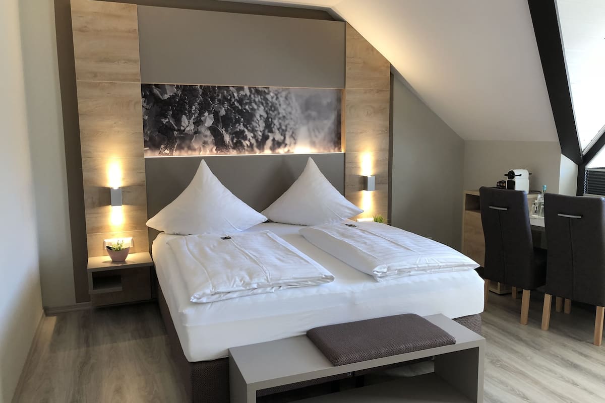 Un dormitorio moderno con cama, mesitas de noche, escritorio y sillas.