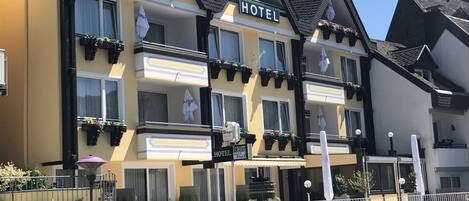 Un hotel con varios balcones, cada uno con barandillas negras y plantas en macetas.