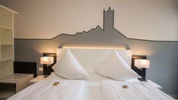 Ein Hotelzimmer mit einem Bett, zwei Nachttischen, zwei Lampen und einem an der Wand hängenden Stadtbild.