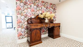 Een houten bureau met bloemen behang en een patroon vloer.