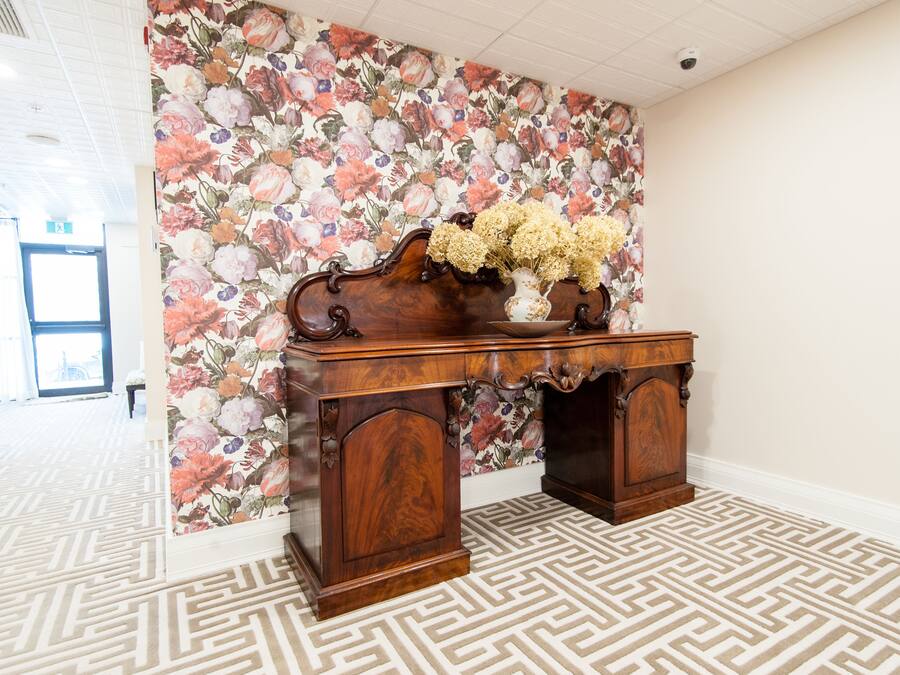 Een houten bureau met bloemen behang en een patroon vloer.