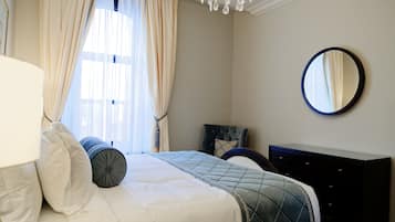 A neatly arranged bedroom with a bed, a dresser, a mirror, and a window with curtains.