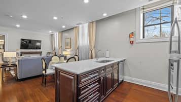 A modern kitchen with a central island, a dining area with a table and chairs, and a living room with a sofa and TV.