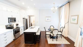 A modern kitchen with white cabinetry, stainless steel appliances, and a central island.