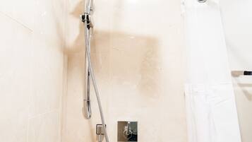 Ducha con cabezal de ducha de mano y panel de control en la pared.