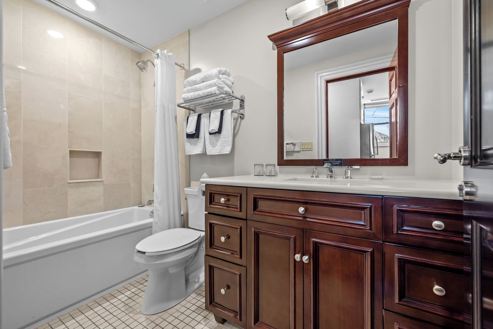A modern bathroom with a bathtub, toilet, vanity with drawers, and a large mirror.