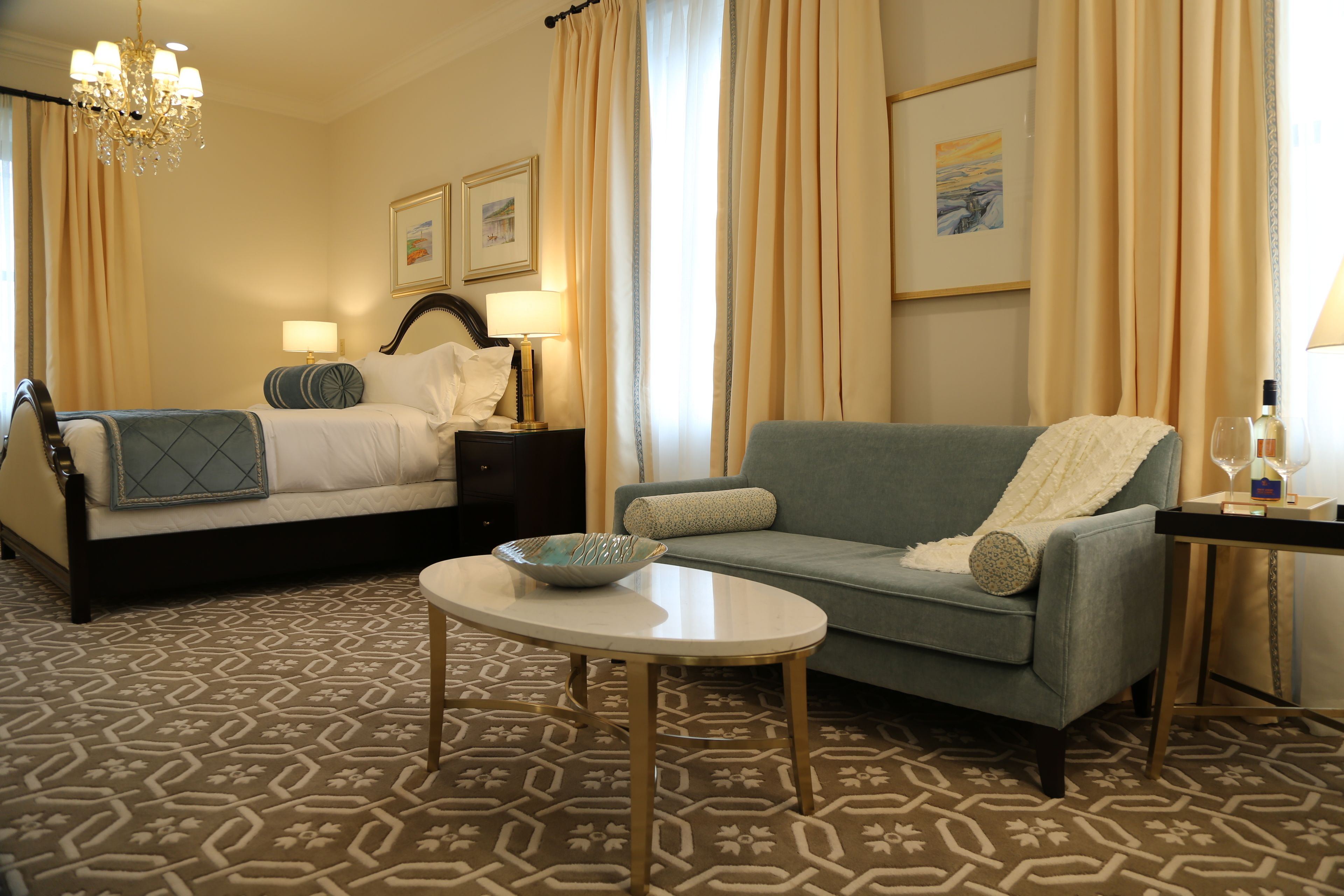Een hotelkamer met een bed, een bank, een tafeltje en een kroonluchter.